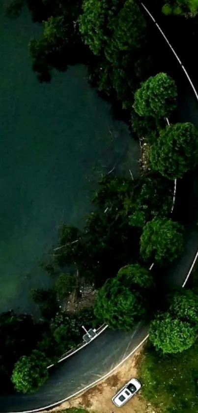 Aerial view of a winding road by a blue lake and green forest.