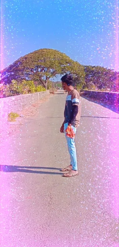 Person standing on a quiet scenic road under a blue sky.