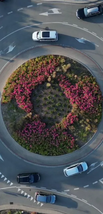 Aerial view of a roundabout with cars and lush flowers.