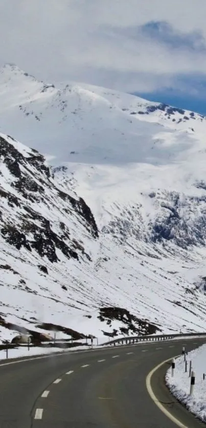 Winding road through snowy mountains under a clear sky.