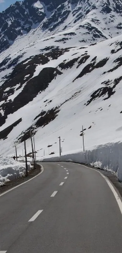 Scenic winding road through snowy mountains and blue sky.