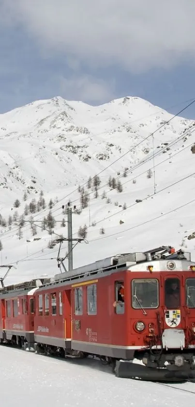 Red train traveling through snowy mountain landscape.