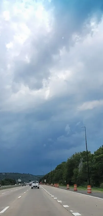 Scenic highway with stormy sky and lush greenery in the background.