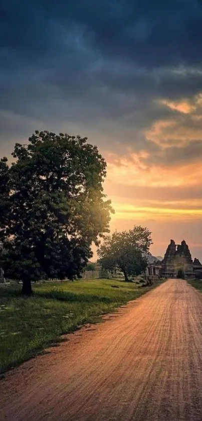 Scenic road under a dramatic sunset sky with trees and distant structures.