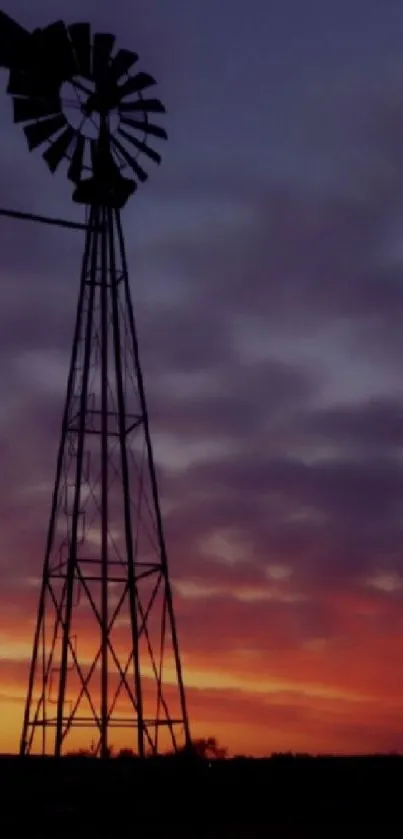 Windmill silhouette against purple sunset sky.