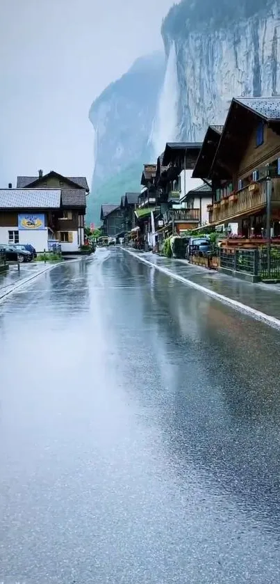 Serene Swiss village with rainy street and mountain backdrop.