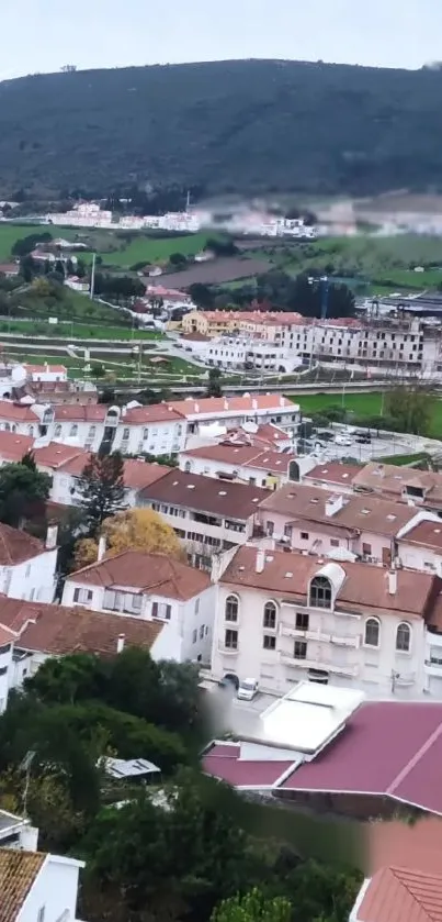 Aerial view of a town with hills and greenery in the background.