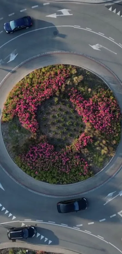 Aerial view of a traffic circle with vibrant flowers in the center.