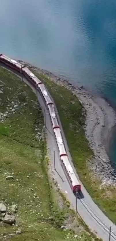 A train on a track beside a turquoise lake and green hills.