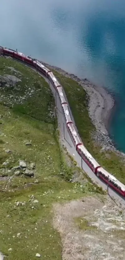 Red train winding along a lush lakeside landscape.