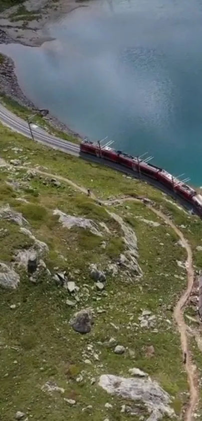 Aerial view of a train passing by a blue lake surrounded by green hills.