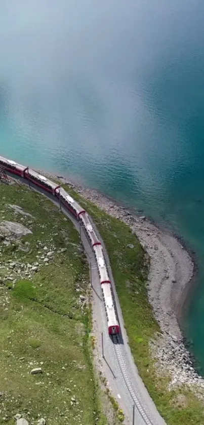 Train curving by a turquoise lake and green landscape.