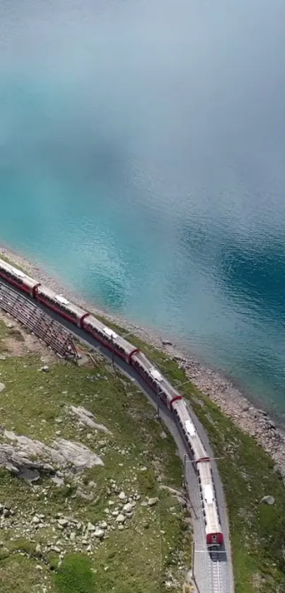 Red train passing by a turquoise lake with scenic views.