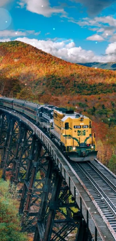 Vibrant train on bridge amidst autumn mountain landscape.