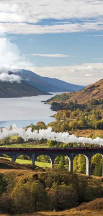 Train crossing a scenic viaduct with mountains and a valley in the background.