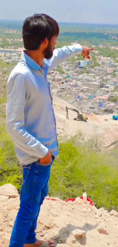 Man pointing towards a distant village landscape from a hilltop.