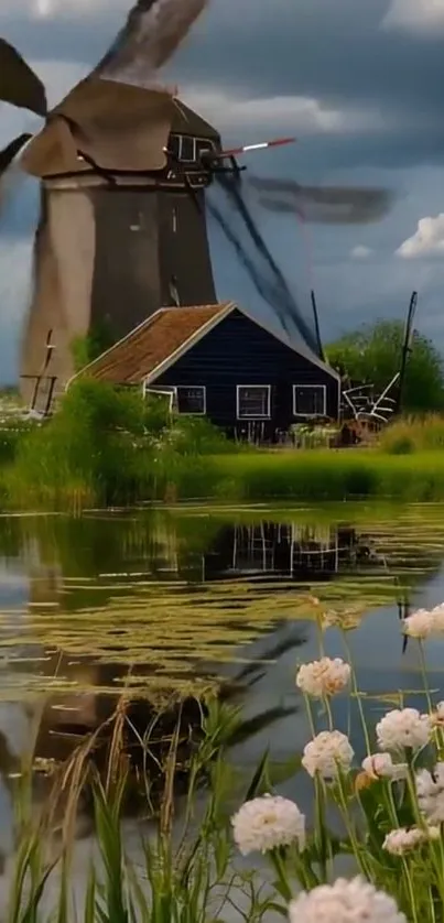 Windmill by a lake with flowers in foreground.