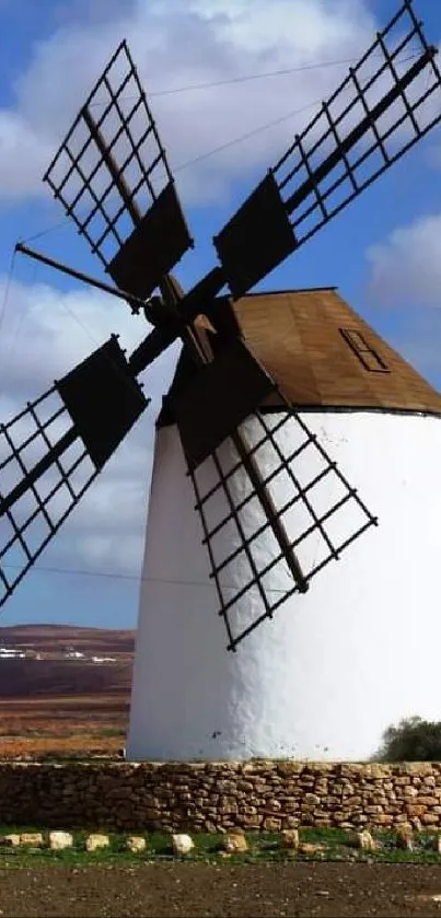 Windmill against a scenic sky with hills in the background, ideal for mobile wallpaper.