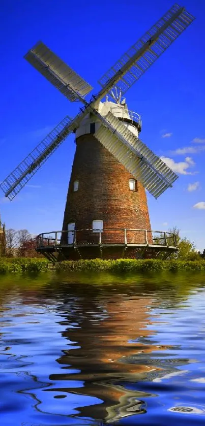 Scenic windmill with mirror-like river reflection under a vibrant blue sky.