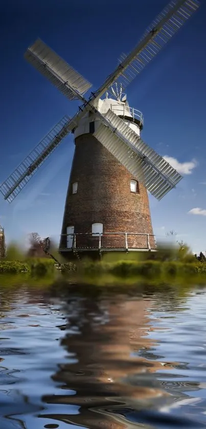 Windmill with reflection under clear blue sky and tranquil water surface.