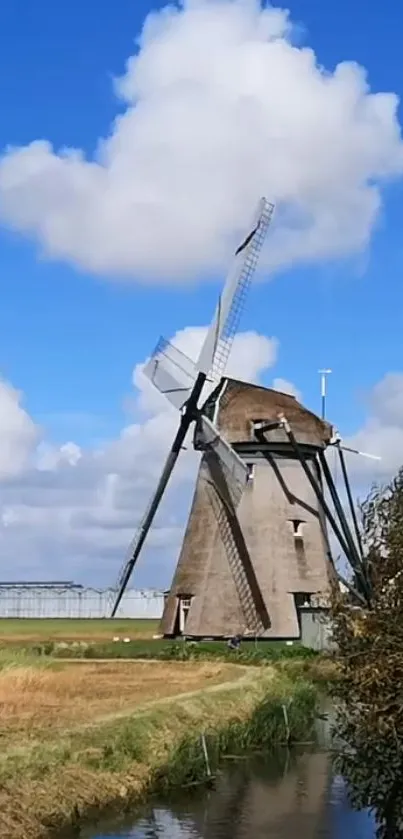 Traditional windmill under a blue sky with fluffy clouds, surrounded by fields.