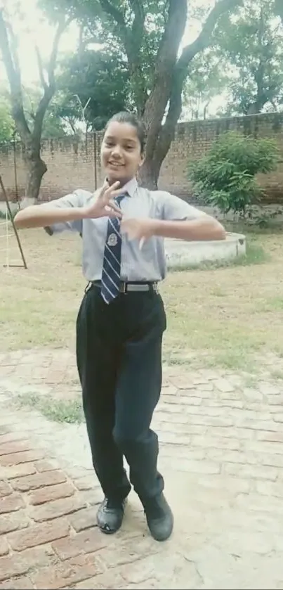 Student in uniform outdoors in a garden setting.