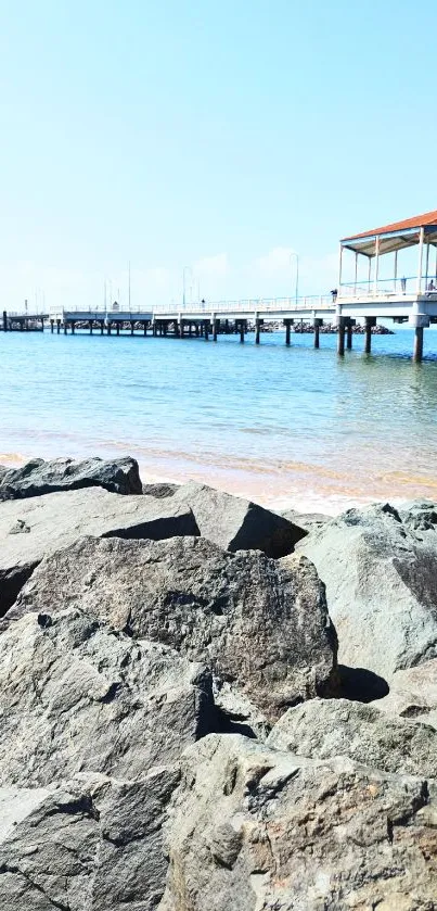 Scenic view of seaside pier and tranquil rocky beach.