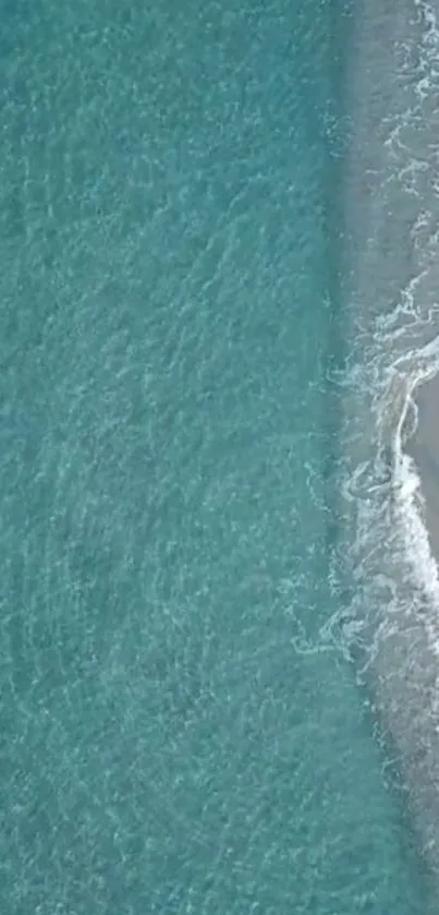 Aerial view of turquoise ocean waves meeting sandy beach.