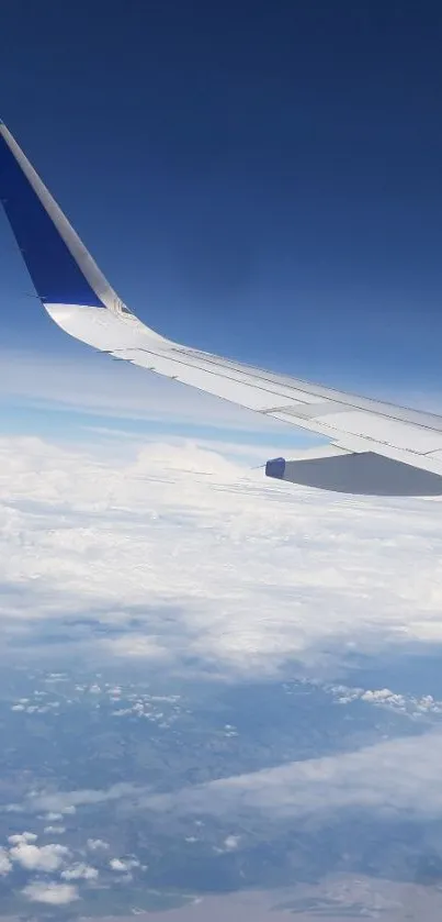 Airplane wing soaring above clouds and blue sky.