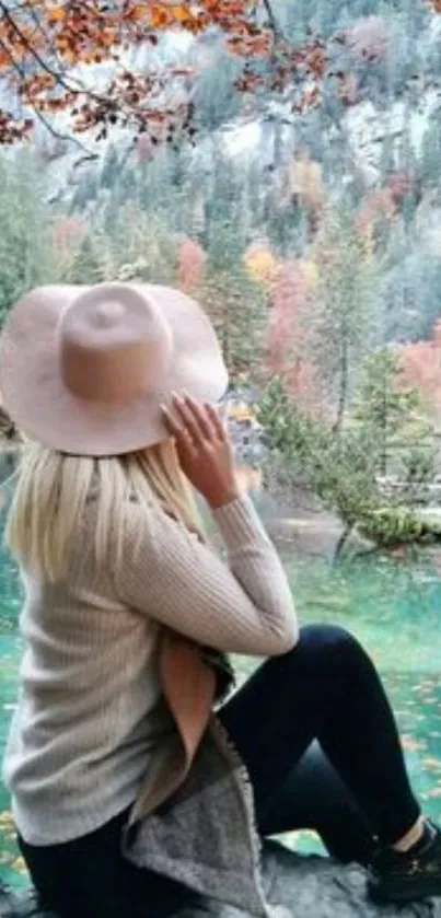 Woman sits by a tranquil autumn lake surrounded by colorful trees.