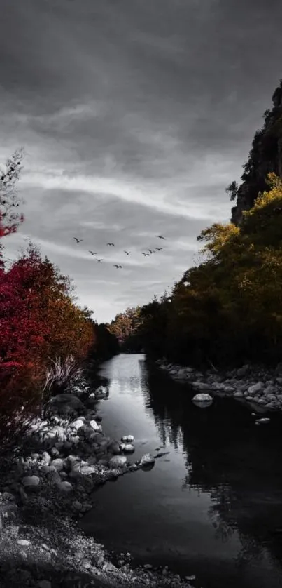 Serene autumn river with red foliage and distant mountains.