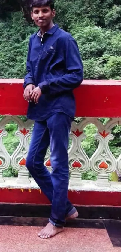 Man standing on scenic balcony with lush greenery in background.