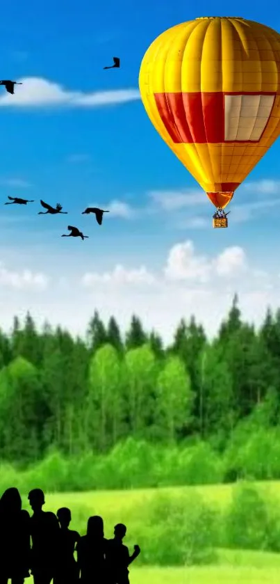 Hot air balloon over a green forest landscape with silhouette of people.