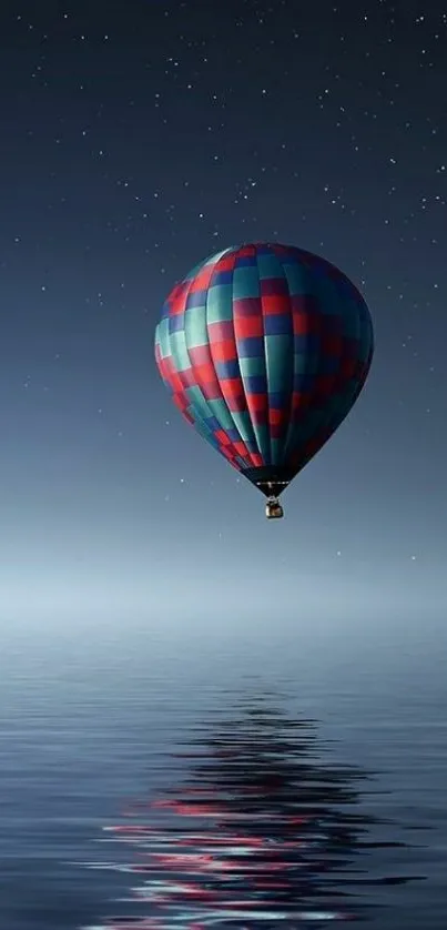 Hot air balloon drifting over reflective water under a starlit dark blue sky.