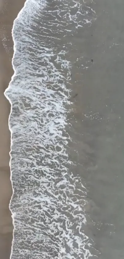 Aerial view of serene beach waves and sand on coastline.