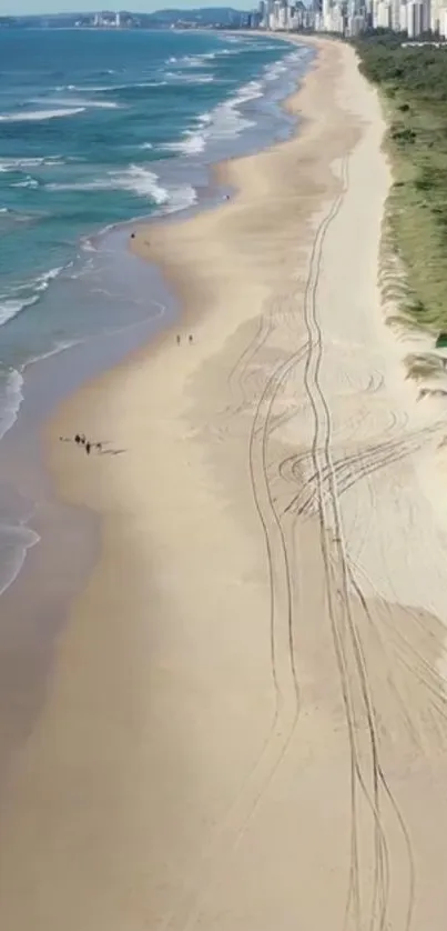 Aerial view of expansive beach with golden sand and blue ocean waves.