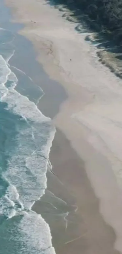 Aerial view of tranquil beach with blue ocean waves and sandy shoreline.