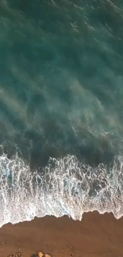 Aerial view of turquoise ocean waves hitting a sandy beach.