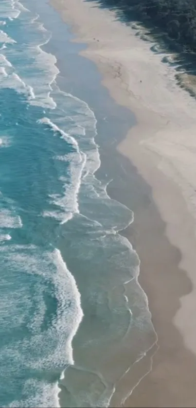 Aerial view of wavy blue ocean meeting a sandy beach under a clear sky.