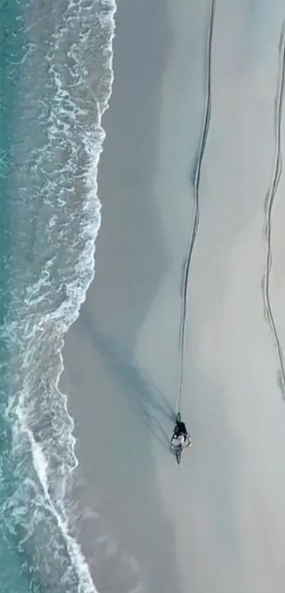 Aerial view of a bicycle path on a serene beach with ocean waves.