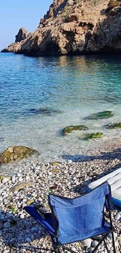 Serene beach with clear blue water and a beach chair on a rocky shoreline.