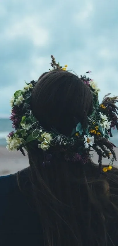 Floral crown by the ocean on a cloudy beach, capturing serene natural beauty.