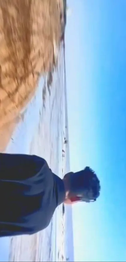 Man overlooking ocean on a serene beach with clear blue sky.