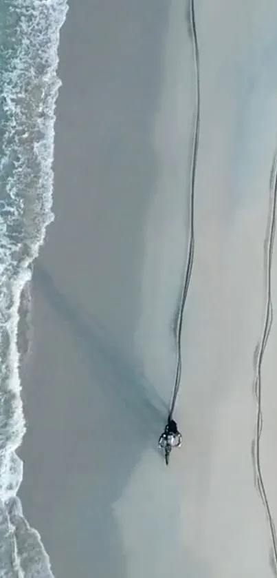 A motorcycle rides along a serene beach with ocean waves.