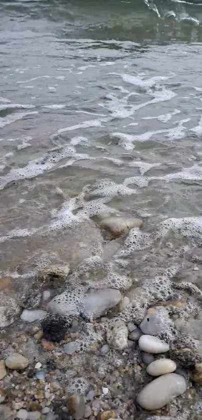 Beach pebbles with foamy waves in tranquil setting.