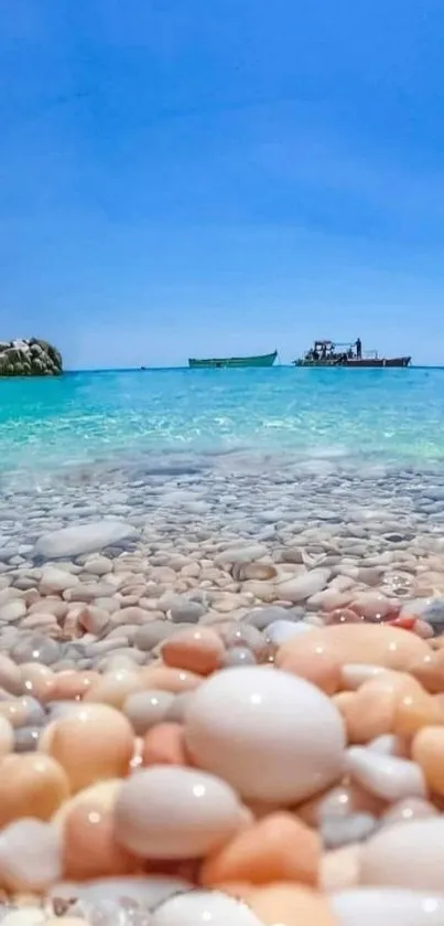 Colorful pebble beach with turquoise waters and boats under a blue sky.