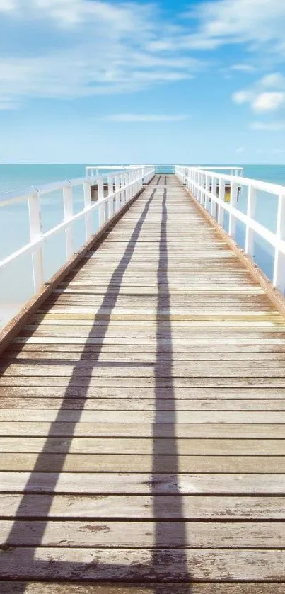 Tranquil wooden pier extending into the ocean with a blue sky background.