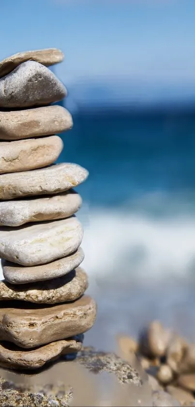 Stack of smooth stones by the ocean with a clear blue sky.