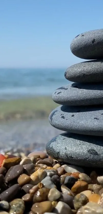 Balanced stones on a peaceful pebble beach with ocean and blue sky backdrop.