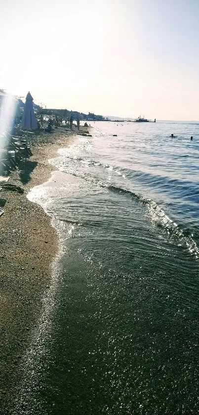 Serene beach scene with sunlit waves and sandy shore.